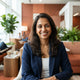 A smiling South Asian woman in a bright, modern airport lounge, representing a satisfied customer for a travel brand.