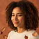 Portrait of a diverse woman smiling softly, with warm-toned background.