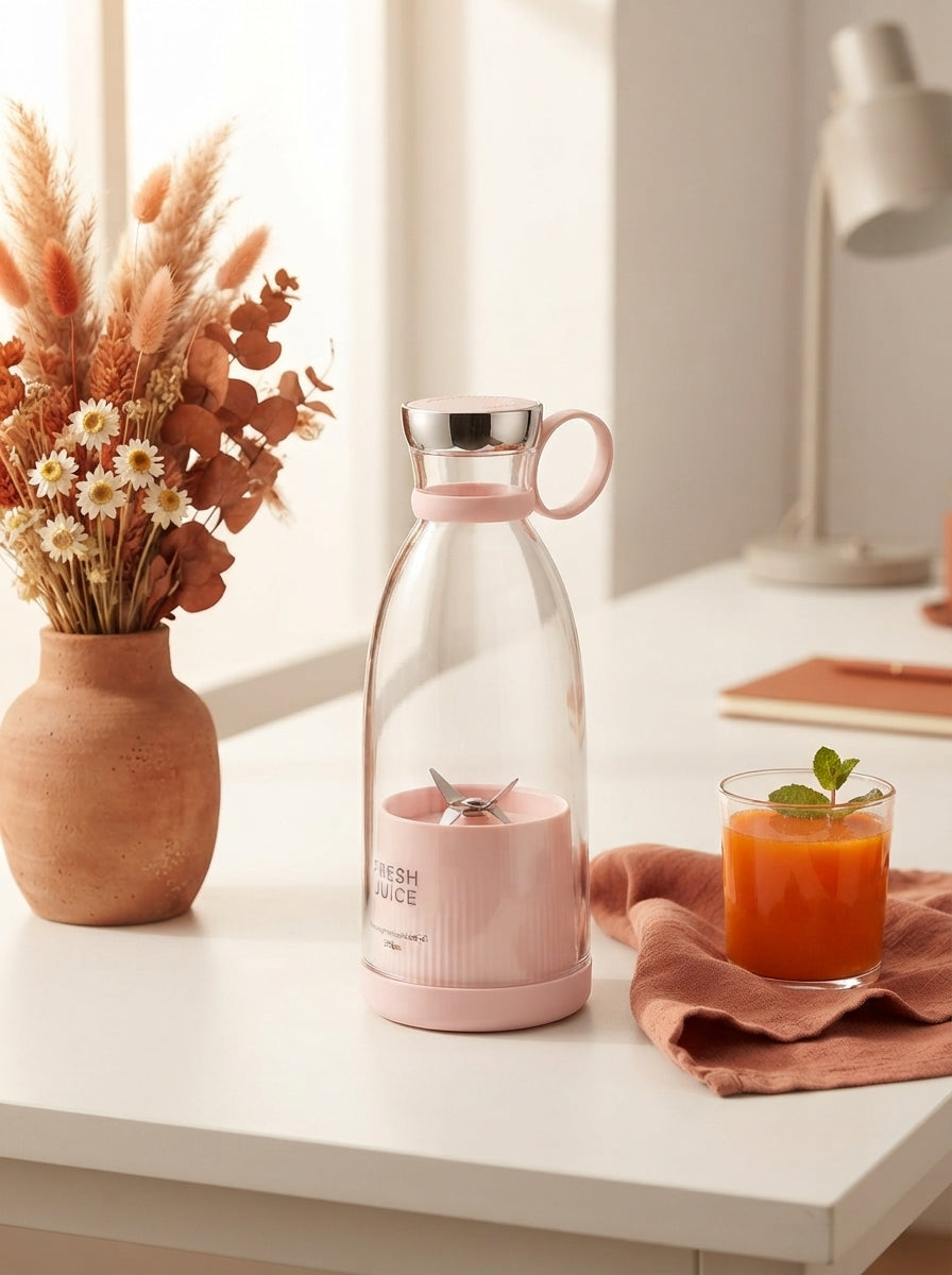 A portable mini blender on a clean desk with terracotta and burnt sienna decor, next to a glass of fresh juice.